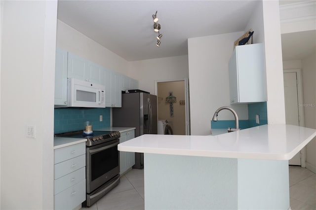 kitchen with stainless steel appliances, separate washer and dryer, a peninsula, light tile patterned floors, and decorative backsplash