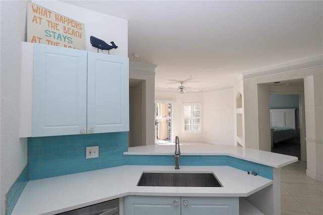 kitchen featuring a sink, a peninsula, ornamental molding, and light countertops