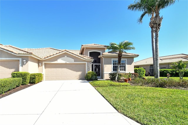 mediterranean / spanish-style home featuring stucco siding, a front lawn, a tile roof, concrete driveway, and a garage