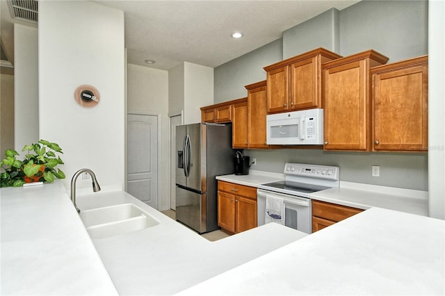 kitchen featuring a sink, white appliances, brown cabinets, and light countertops