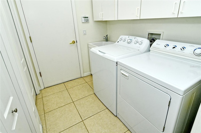 clothes washing area featuring washer and clothes dryer, light tile patterned floors, cabinet space, and a sink