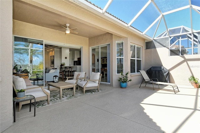 view of patio with a lanai, area for grilling, a ceiling fan, and an outdoor living space