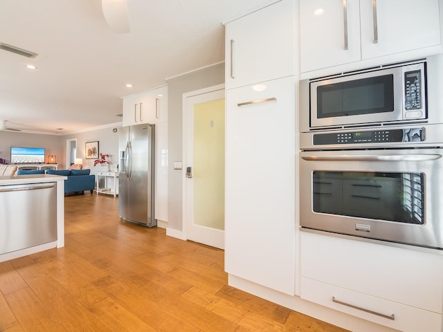 kitchen with visible vents, light wood-style flooring, white cabinets, appliances with stainless steel finishes, and open floor plan