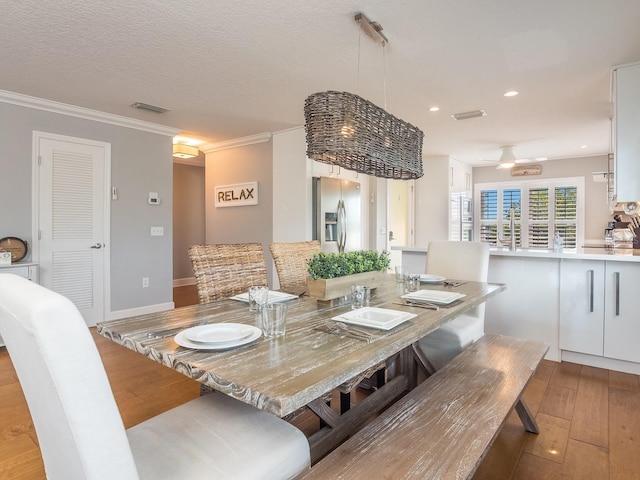 dining room with visible vents, ornamental molding, a textured ceiling, recessed lighting, and wood-type flooring