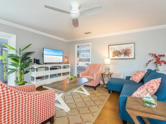 living area featuring a textured ceiling, crown molding, ceiling fan, and wood finished floors