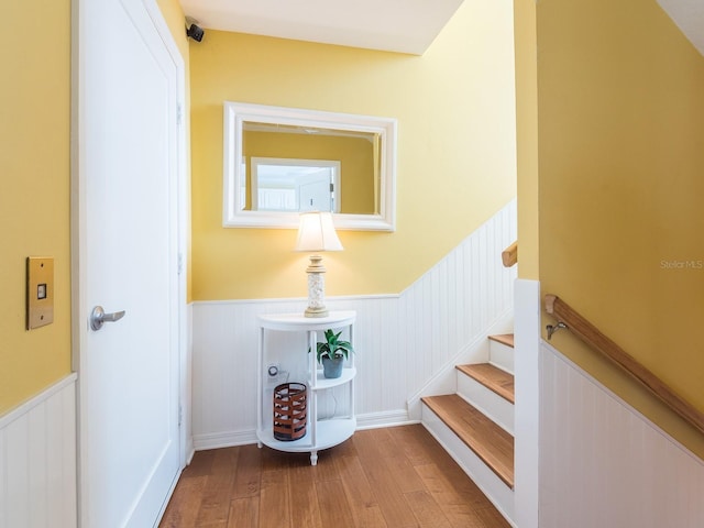 stairs with a wainscoted wall and wood finished floors