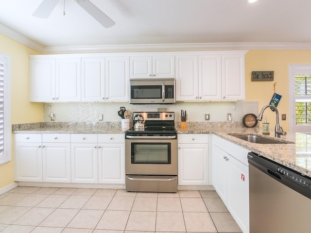 kitchen with a sink, stainless steel appliances, crown molding, and light tile patterned floors