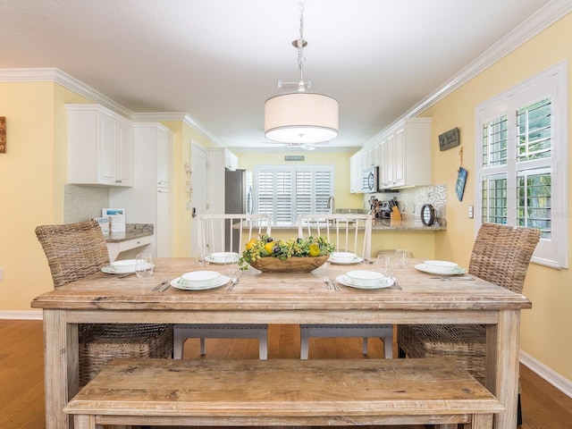 dining room featuring plenty of natural light, baseboards, light wood-style floors, and ornamental molding