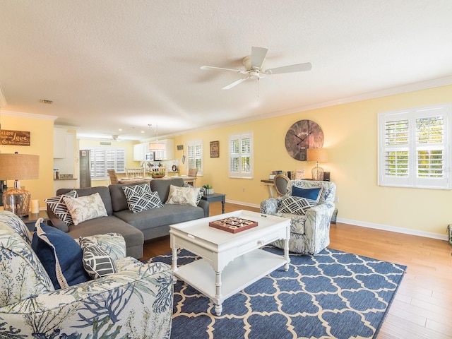 living area featuring wood finished floors, a ceiling fan, and ornamental molding