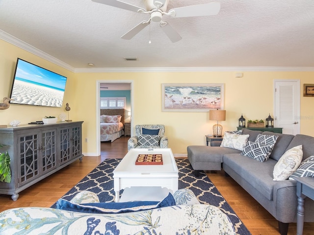 living room with visible vents, crown molding, ceiling fan, wood finished floors, and a textured ceiling