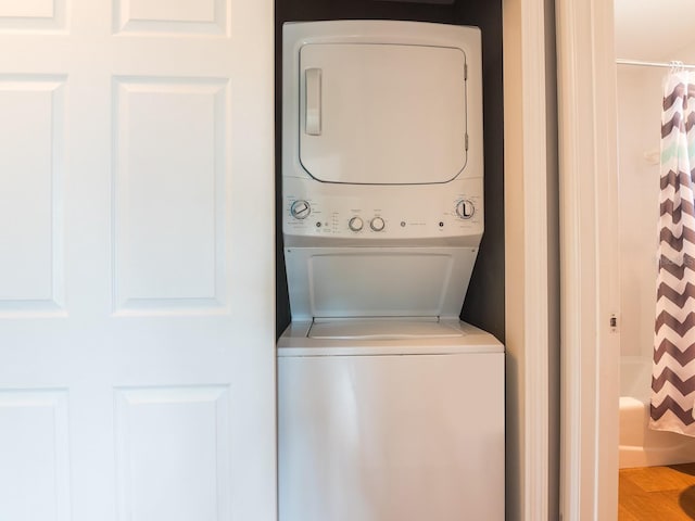 laundry area featuring stacked washer / dryer, laundry area, and wood finished floors