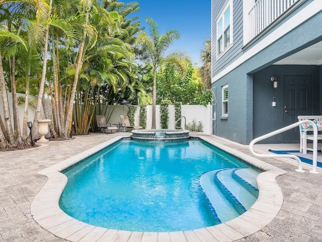 view of swimming pool featuring a patio, a fenced backyard, and a pool with connected hot tub