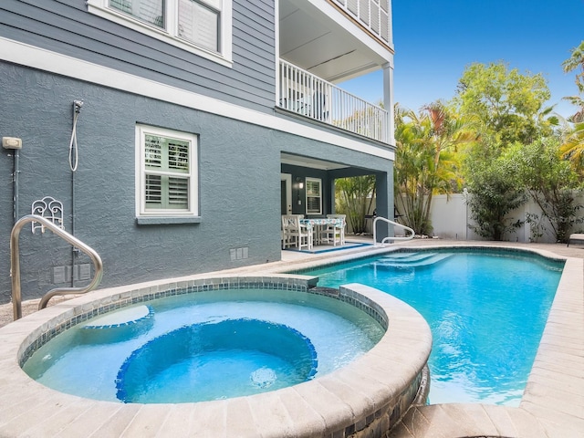 view of swimming pool with a pool with connected hot tub, a patio, and fence