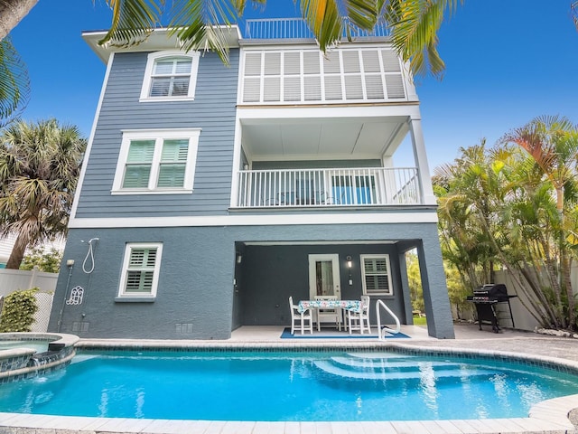 back of house featuring a patio, a pool with connected hot tub, a balcony, and fence