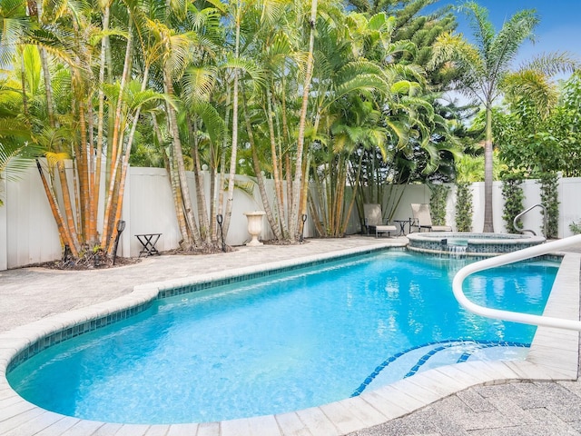 view of swimming pool featuring a pool with connected hot tub and a fenced backyard