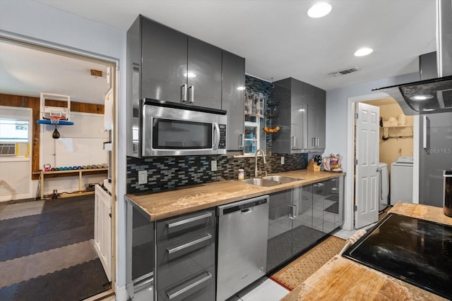 kitchen featuring a sink, stainless steel appliances, light countertops, decorative backsplash, and washer / dryer