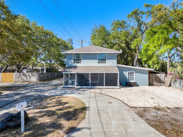 view of front facade with stucco siding, fence, and a sunroom