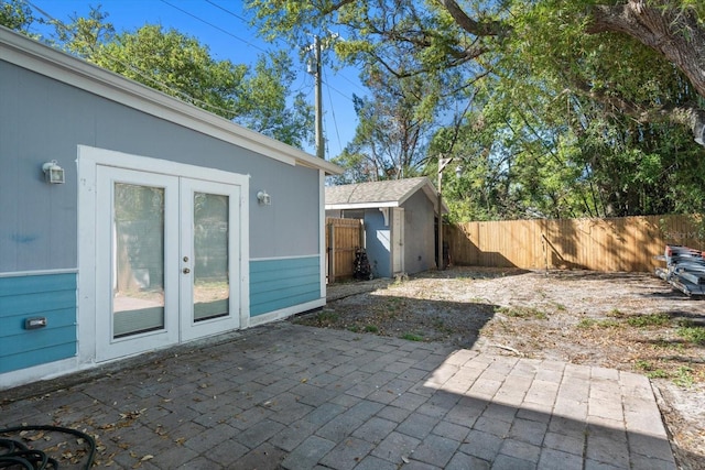 view of patio with a shed, french doors, an outdoor structure, and a fenced backyard