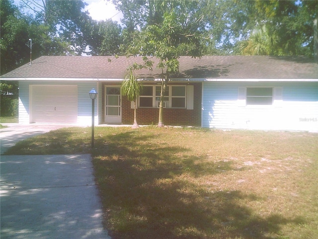 ranch-style home with brick siding, an attached garage, concrete driveway, and a front yard