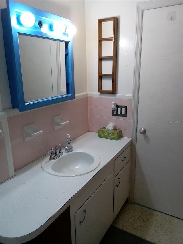 bathroom with vanity, a wainscoted wall, tile walls, and speckled floor