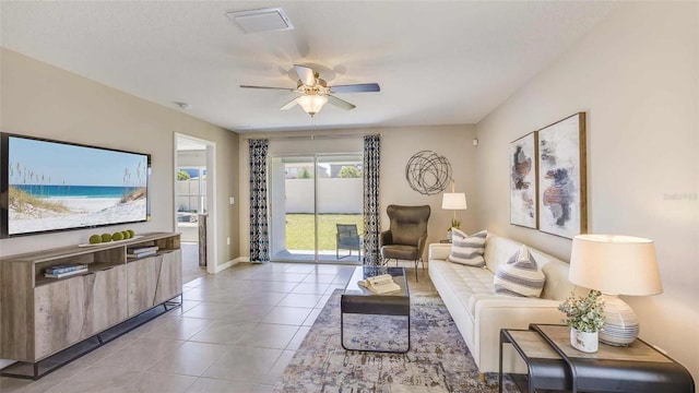 living room featuring tile patterned floors, visible vents, baseboards, and ceiling fan