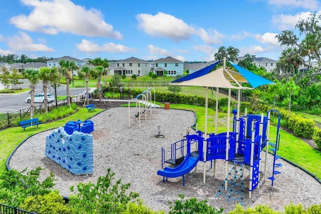 communal playground featuring a residential view, a lawn, and fence