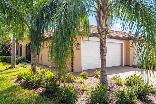 exterior space with stucco siding, a tile roof, decorative driveway, and a garage