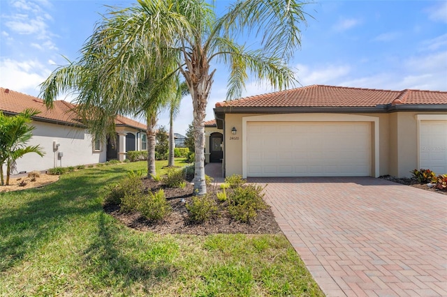 view of front of property with stucco siding, decorative driveway, a garage, and a tiled roof