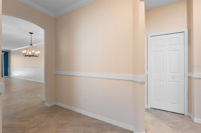 hallway with baseboards, arched walkways, an inviting chandelier, and ornamental molding