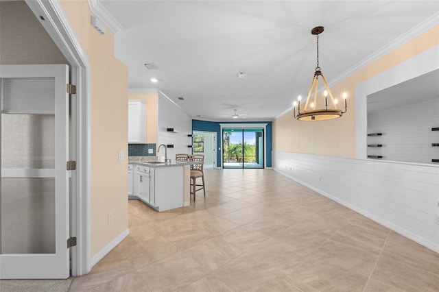 kitchen with a breakfast bar, a sink, white cabinetry, crown molding, and open floor plan