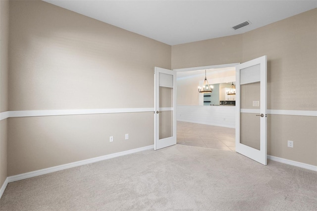 tiled empty room featuring visible vents, french doors, carpet flooring, baseboards, and a chandelier