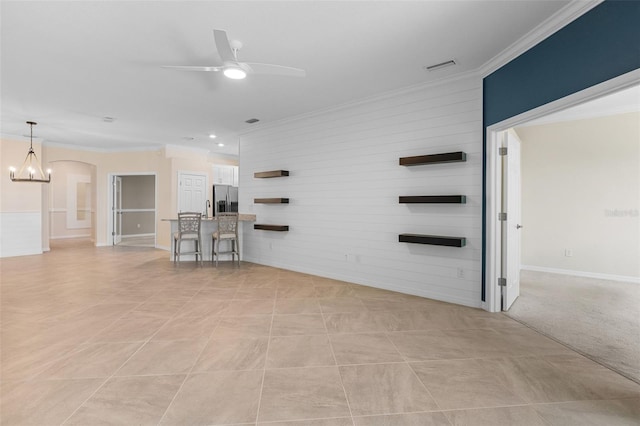 unfurnished room with crown molding, ceiling fan with notable chandelier, visible vents, and arched walkways