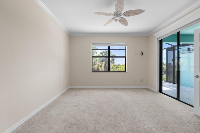 carpeted empty room with baseboards, a ceiling fan, and crown molding