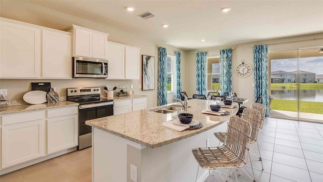 kitchen with light tile patterned floors, visible vents, a sink, white cabinets, and appliances with stainless steel finishes