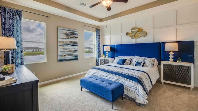 bedroom with a decorative wall, baseboards, visible vents, and carpet floors