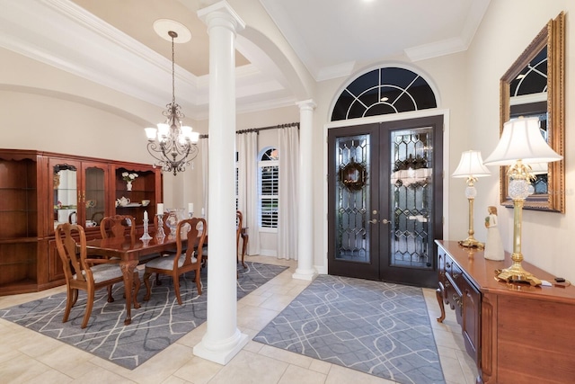 foyer entrance featuring decorative columns, arched walkways, french doors, crown molding, and a chandelier