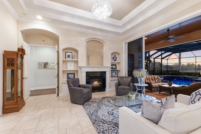 living room with a raised ceiling, built in features, crown molding, and a sunroom