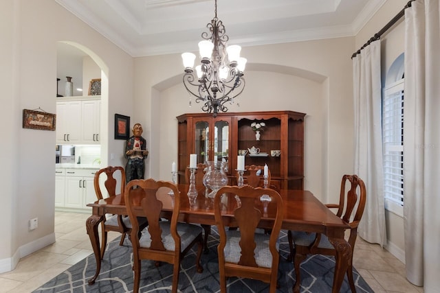 dining room with crown molding, baseboards, a tray ceiling, an inviting chandelier, and arched walkways