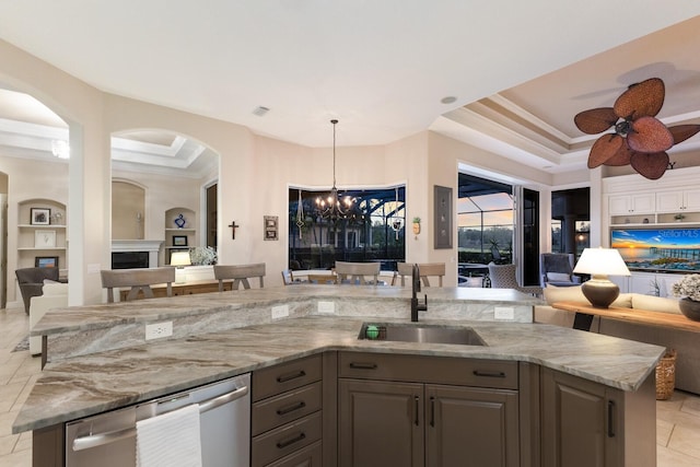 kitchen featuring light stone counters, open floor plan, a tray ceiling, and a sink