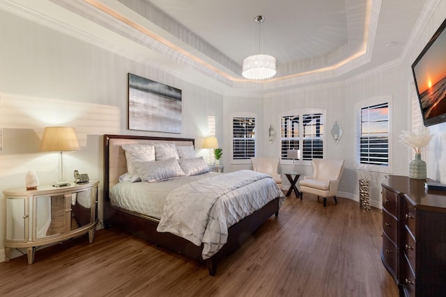 bedroom featuring baseboards, a raised ceiling, wood finished floors, and ornamental molding