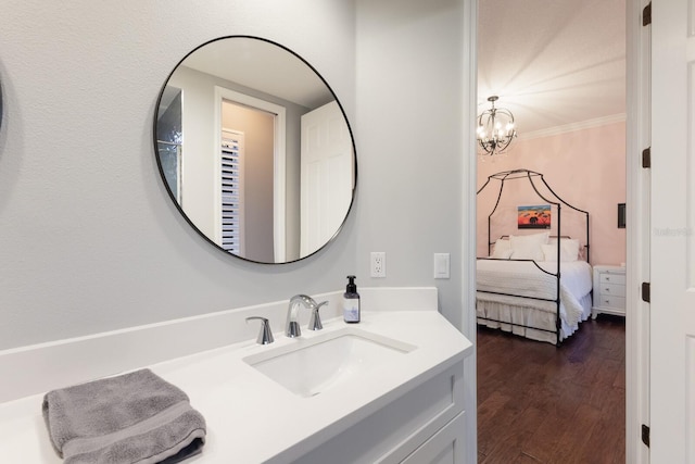 bathroom with a chandelier, wood finished floors, ornamental molding, and vanity