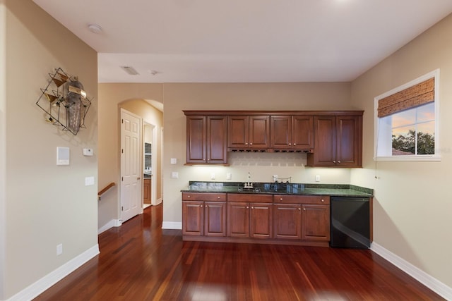 kitchen featuring dark countertops, baseboards, dishwasher, arched walkways, and dark wood-style floors