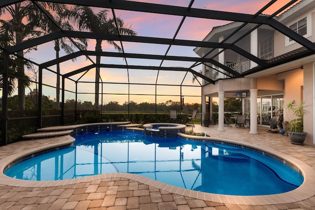 pool at dusk with a lanai, a patio area, and a pool with connected hot tub