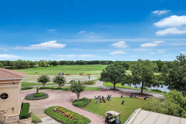 view of property's community with a yard, curved driveway, and golf course view