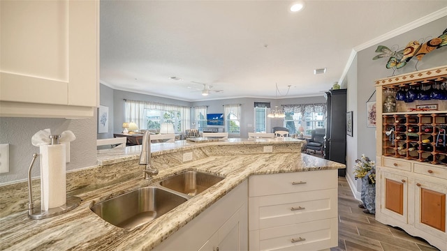 kitchen with a sink, light stone countertops, ornamental molding, and wood tiled floor