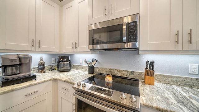 kitchen featuring white cabinets, appliances with stainless steel finishes, and light stone countertops