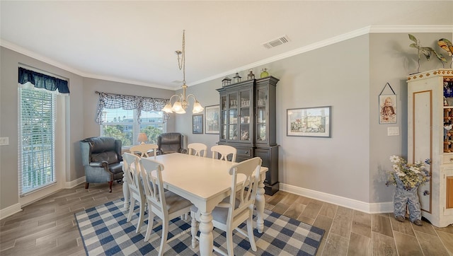 dining space with a notable chandelier, visible vents, crown molding, and wood finish floors