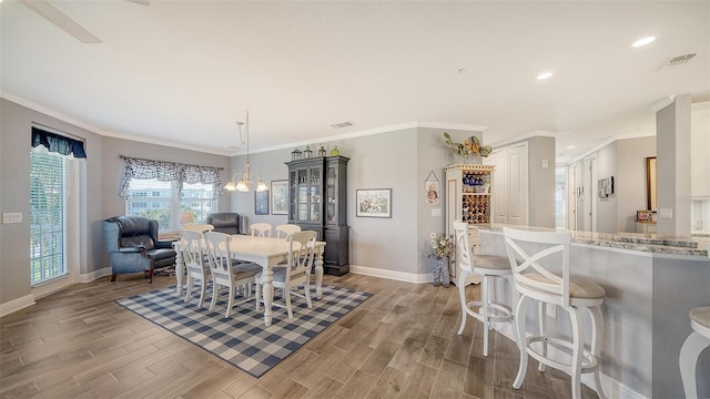 dining area featuring visible vents, a notable chandelier, crown molding, baseboards, and wood tiled floor