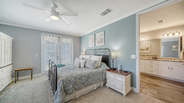 bedroom with baseboards, visible vents, ensuite bath, a sink, and crown molding