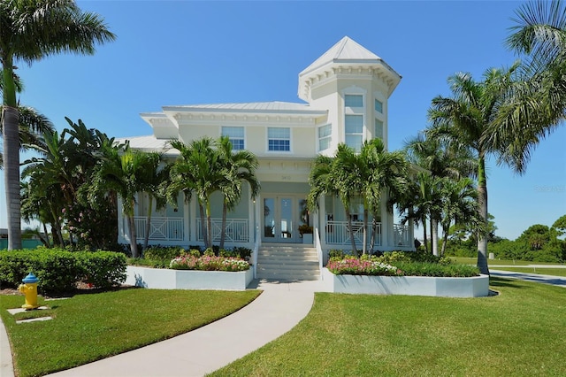 view of front of home featuring a porch, french doors, and a front lawn